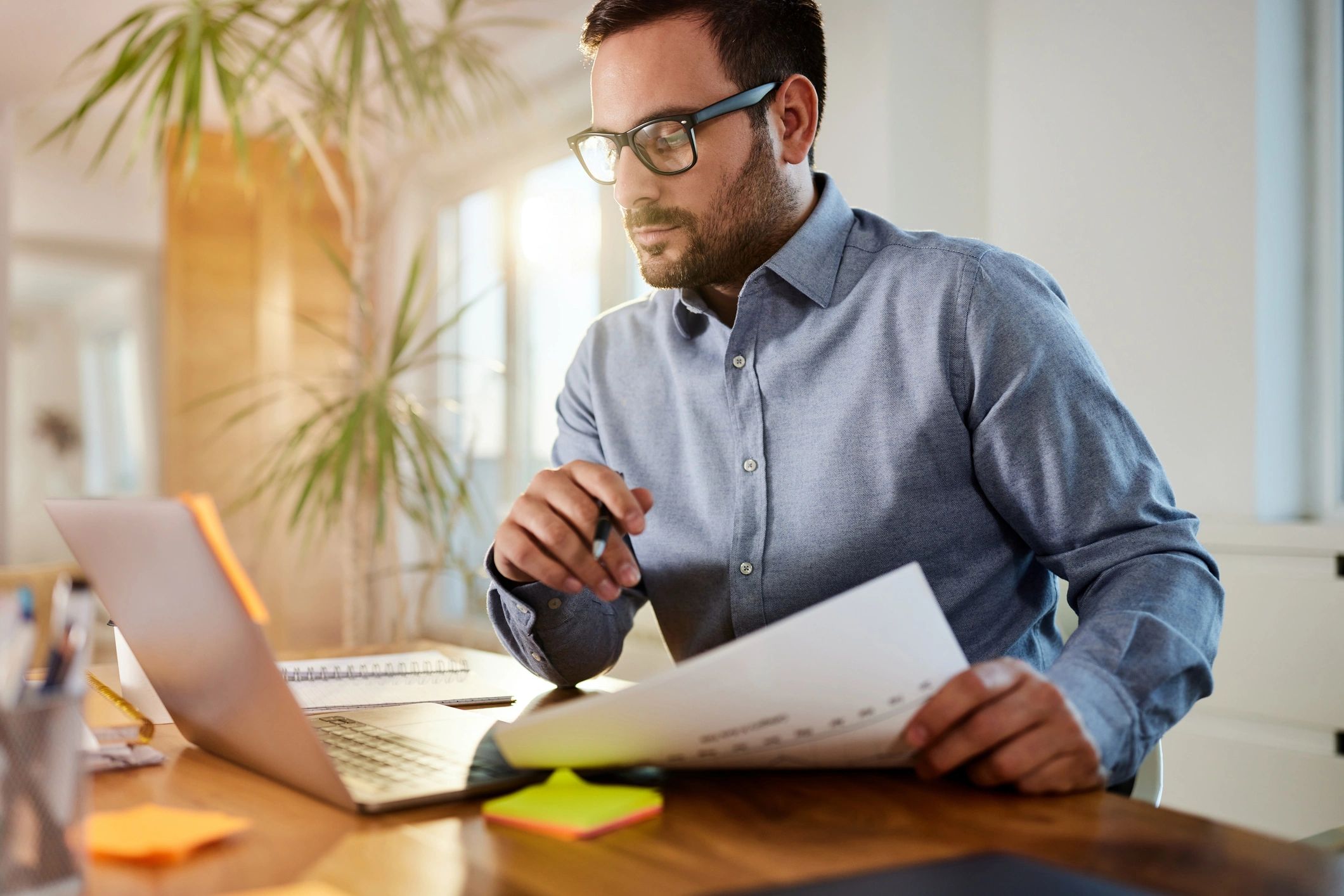 Consultant reviewing contract documents and working on a laptop
