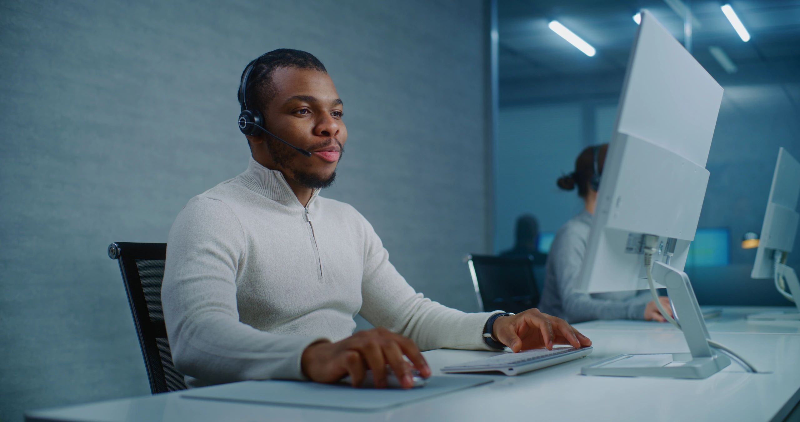 Customer support professional using a headset at a workstation